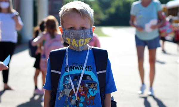 boy smiles while wearing mask